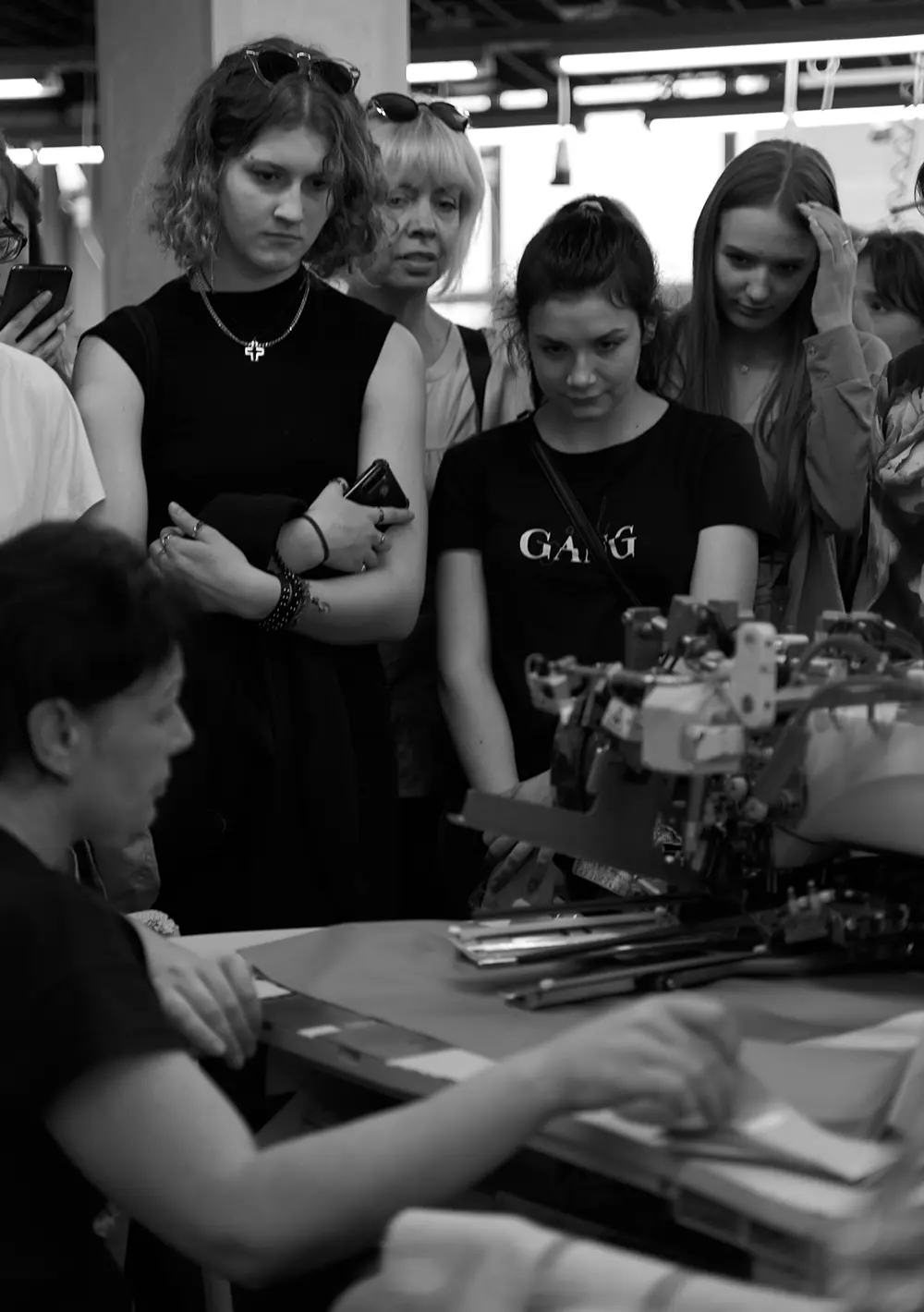 Чорна футболка на студентці, яка уважно спостерігає за роботою швачки Natali Bolgar за машиною.