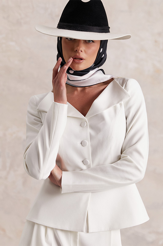 A stylish white Natali Bolgar jacket, white trousers, and a black-and-white scarf come together for a refined spring look.