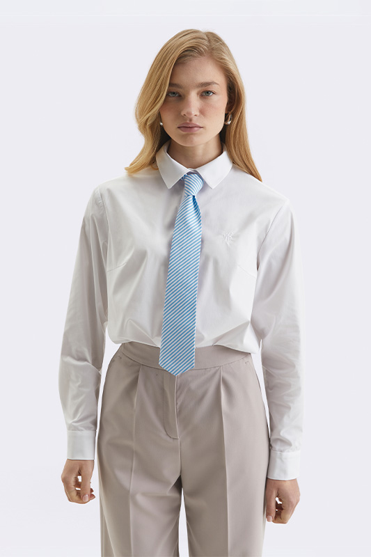A business look from Natali Bolgar: a white shirt, light trousers, and a striped blue tie. The embodiment of a modern office style.