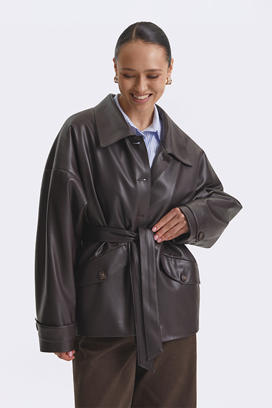 Oversized Natali Bolgar women's jacket in dark brown eco-leather for a stylish spring look. With a belt and a striped shirt.