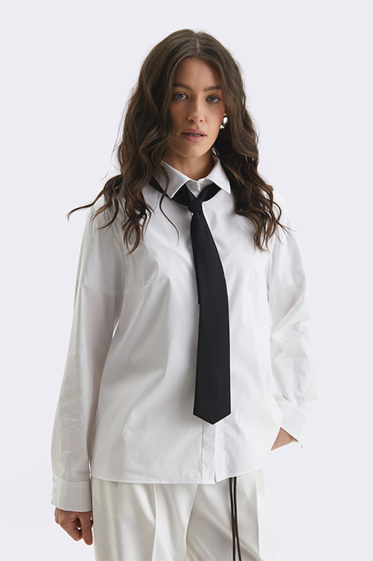 An oversized white shirt from Natali Bolgar with a black tie, creating a stylish everyday look.