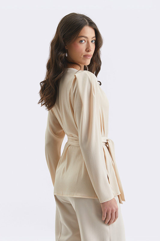 An elegant blouse in a light beige shade with a belt to define the waist, ideal for a look from Natali Bolgar.