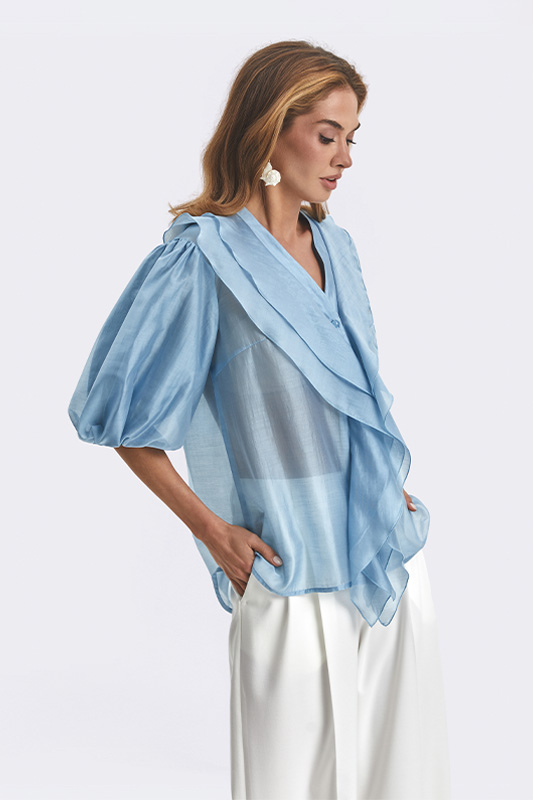 An elegant Natali Bolgar look: a soft light-blue women's blouse with voluminous sleeves paired with wide white trousers for a spring wardrobe.