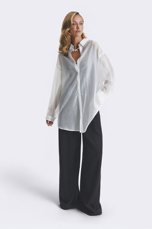 A stylish Natali Bolgar spring look: a sheer, oversized women's shirt and wide black trousers. An elegant and comfortable ensemble.