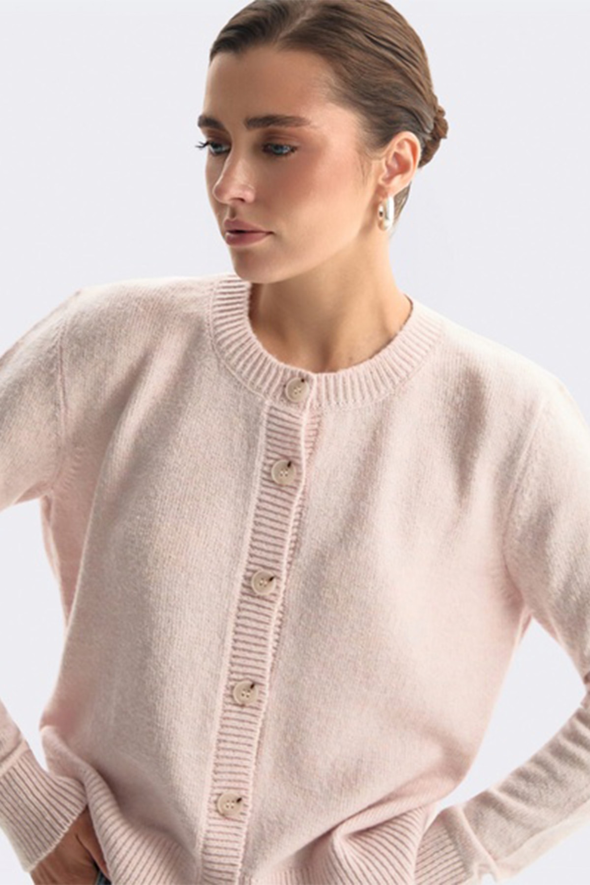 Ніжно-рожевий кардиган з круглим вирізом на ґудзиках і рельєфною планкою, зібране волосся, срібна сережка